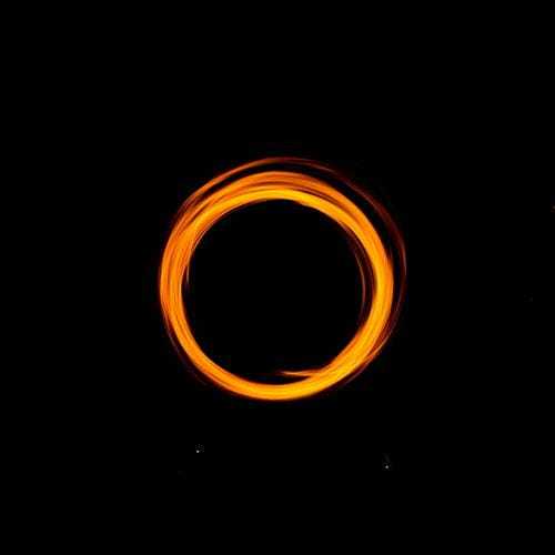 暗闇で輝くオレンジ色の光のサークルの画像