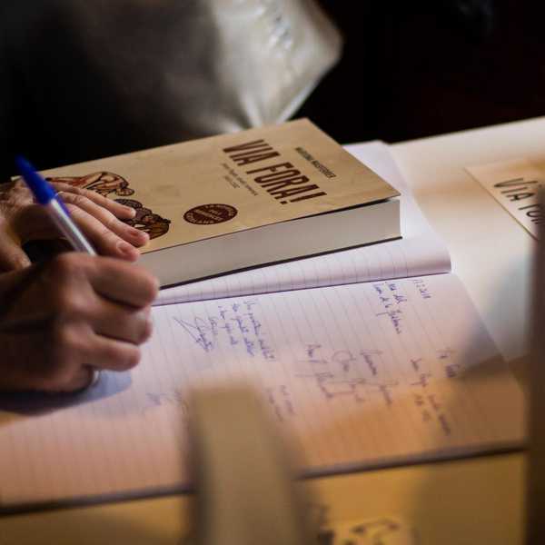 本を読みながらノートに筆記する女性の手と握られたペン